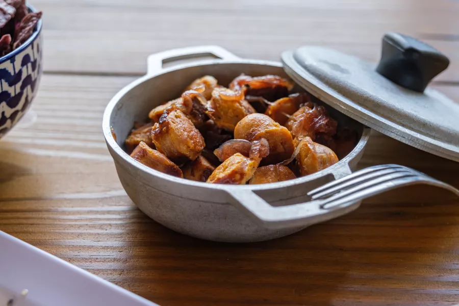A traditional aluminium pot filled with guineos en escabeche, a green banana dish from Puerto Rico.