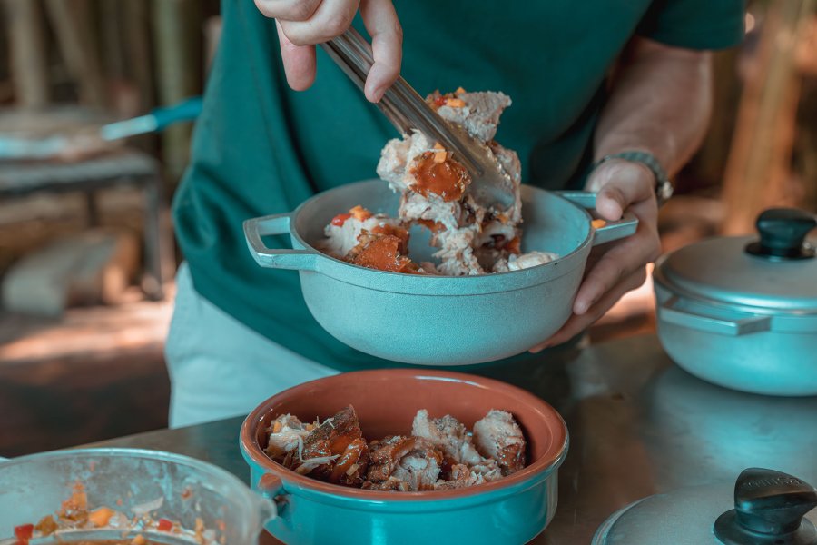 A person serving a portion of pernil, a slow roasted pork dish from Puerto Rico.