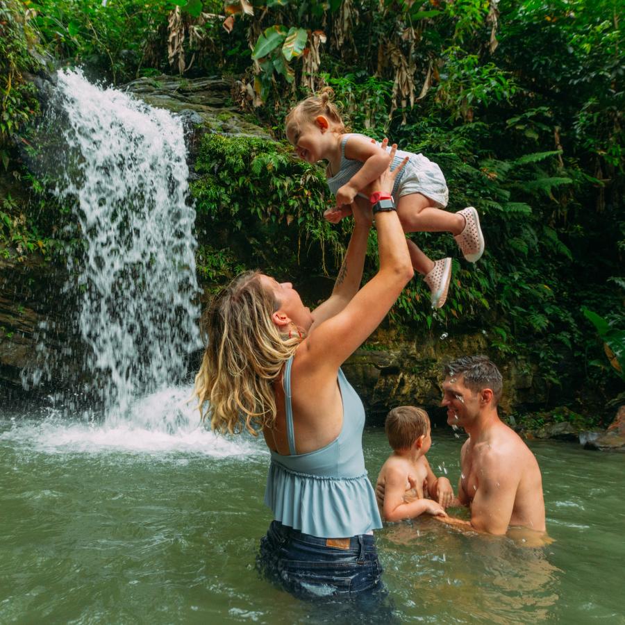 Family enjoying waterfall pool in El Yunque National Forest during a weekend in Puerto Rico